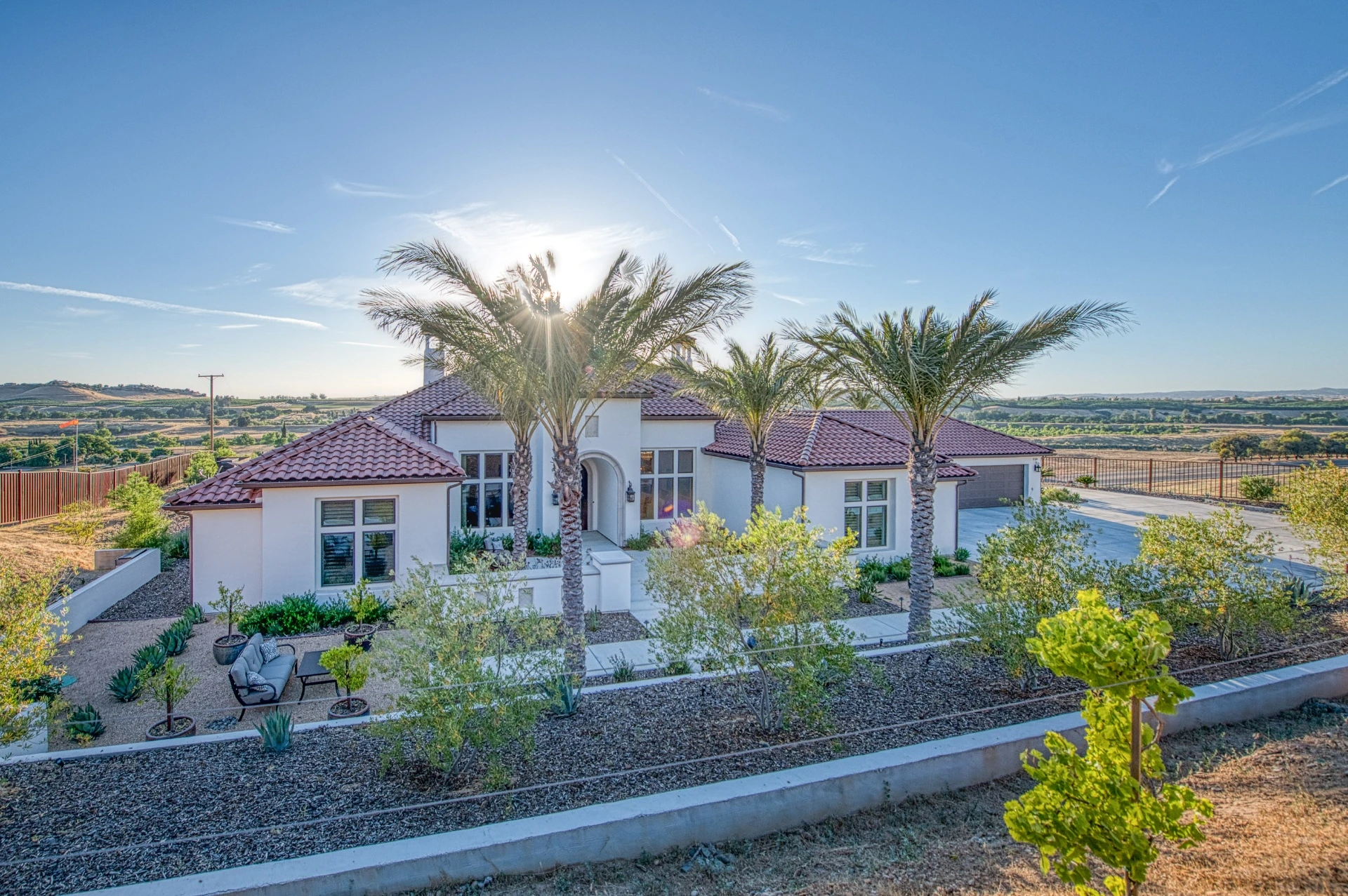 Single-story custom estate on a Central Valley hillside framed by date palms at sunset