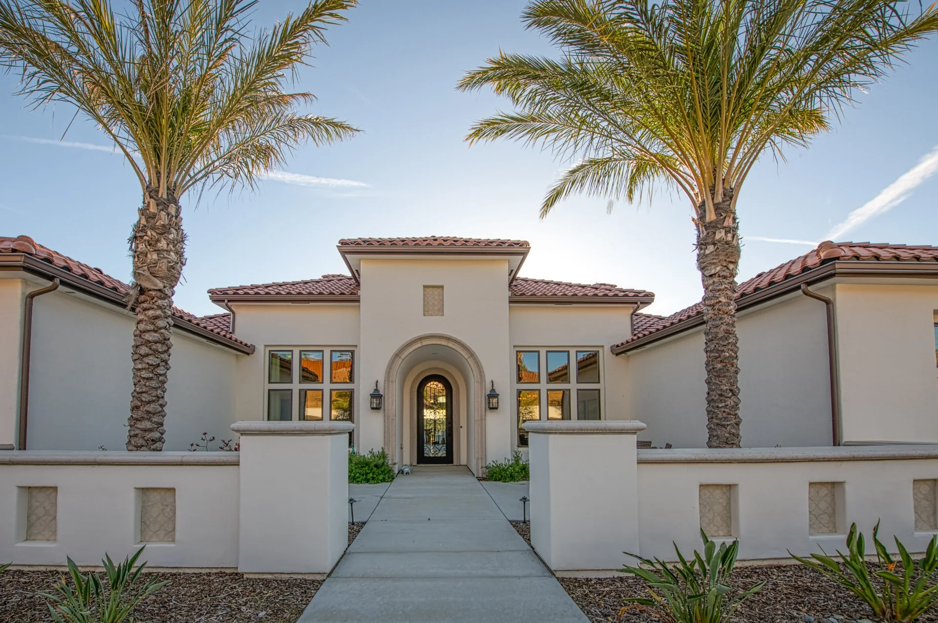 Symmetrical custom-home entrance framed by palm trees and an arched doorway in California’s Central Valley.