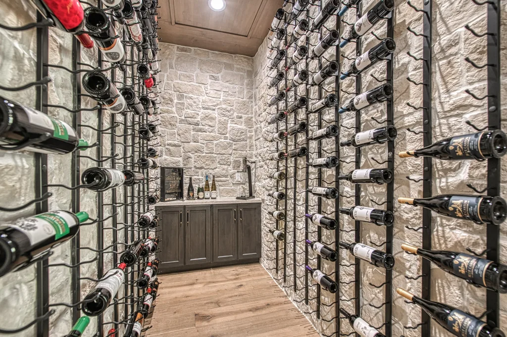 Custom wine cellar featuring stone walls, wood cabinetry, and floor-to-ceiling bottle storage.