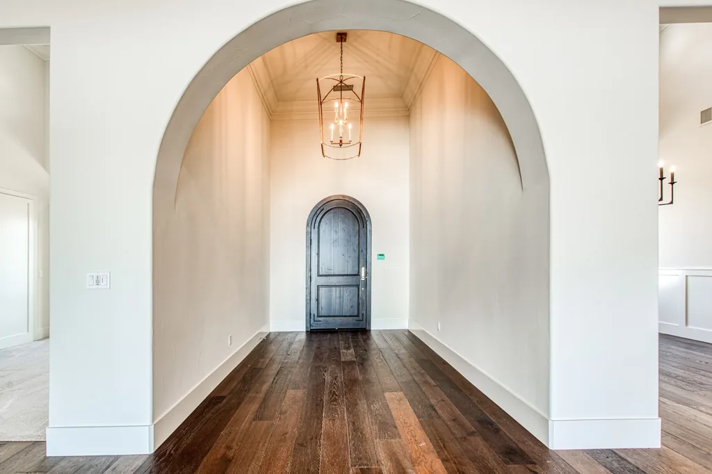 Arched entry foyer at Ashlan Estate leading to a stained arched front door in Sanger, California.