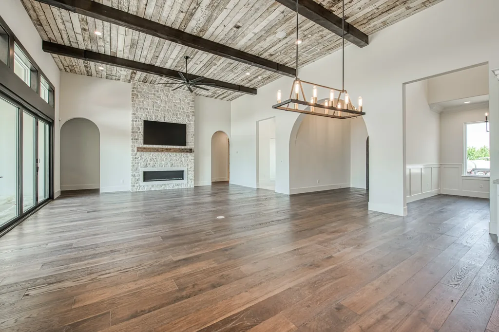 Great room at Ashlan Estate with a limestone fireplace, reclaimed wood ceiling, and dark timber beams in Sanger, California.