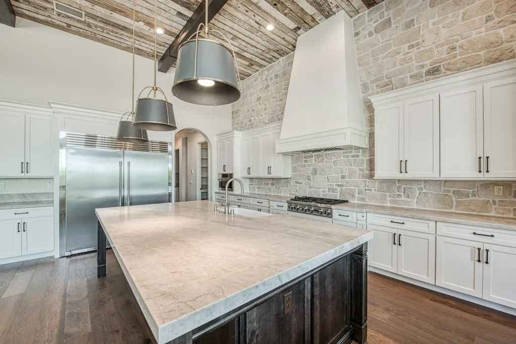 Angled view of the kitchen island, pendant lighting, and custom cabinetry at Ashlan Estate.
