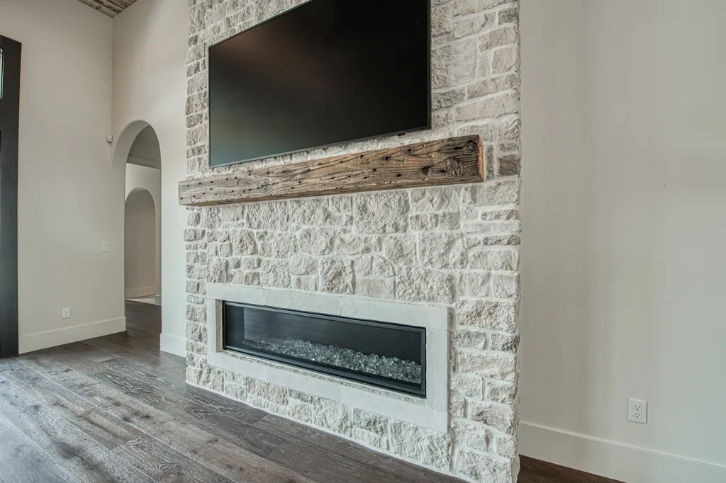 Limestone fireplace with a reclaimed wood mantel and linear firebox at Ashlan Estate.