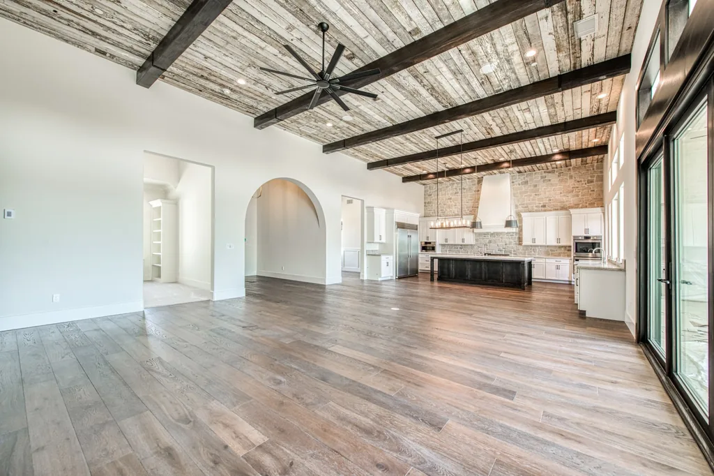 Open living and kitchen space beneath timber beams and a reclaimed plank ceiling at Ashlan Estate.