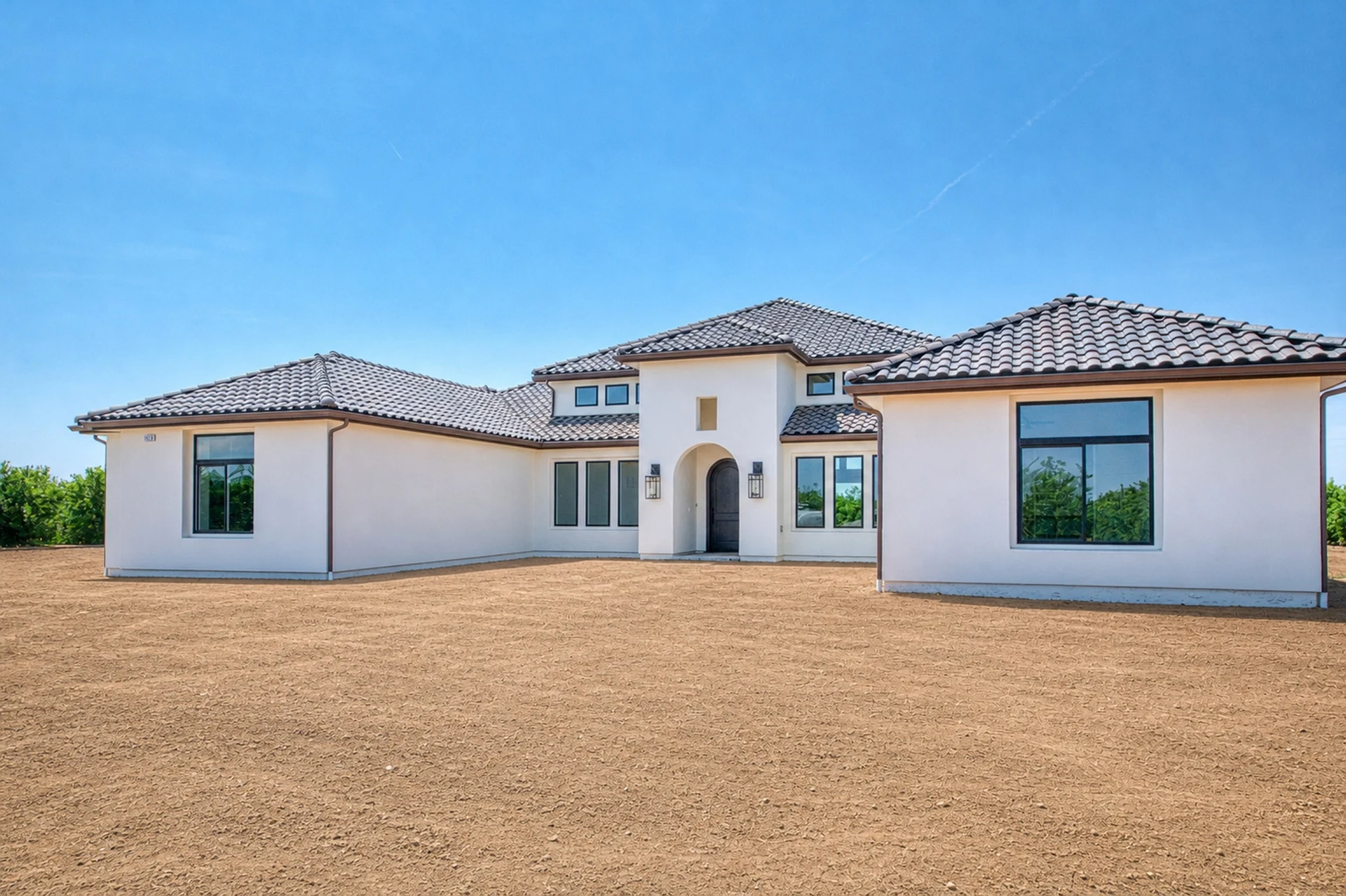 Exterior of Ashlan Estate, a custom home with a recessed arched entry tower and low tile roofline in Sanger, California.