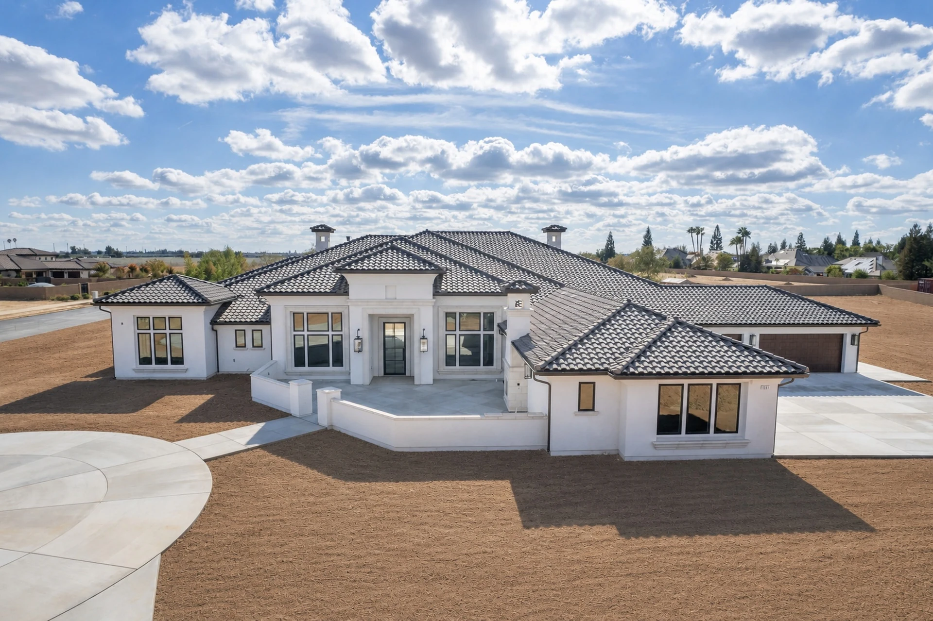 Exterior of Queens Estate, a single-story custom home with a grey tile hip roof and covered stone entry portico in Clovis, California.