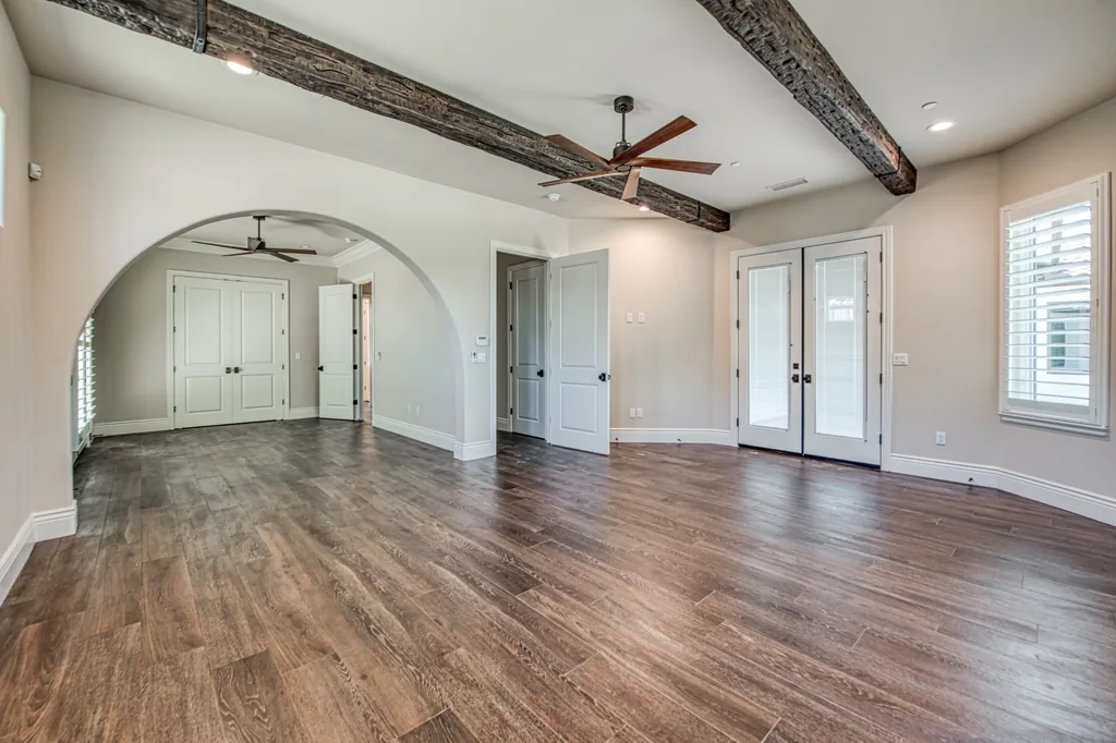 Living space at Devonshire Estate with reclaimed ceiling beams, an arched opening, and wide-plank floors.