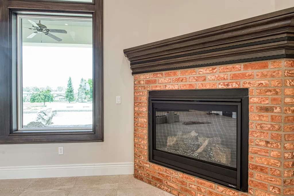 Brick-clad fireplace with dark wood mantel in the Devonshire Estate great room.