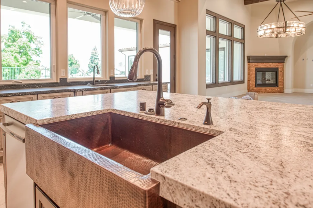 Hammered copper farmhouse sink set in the granite island at Devonshire Estate in Fresno, California.