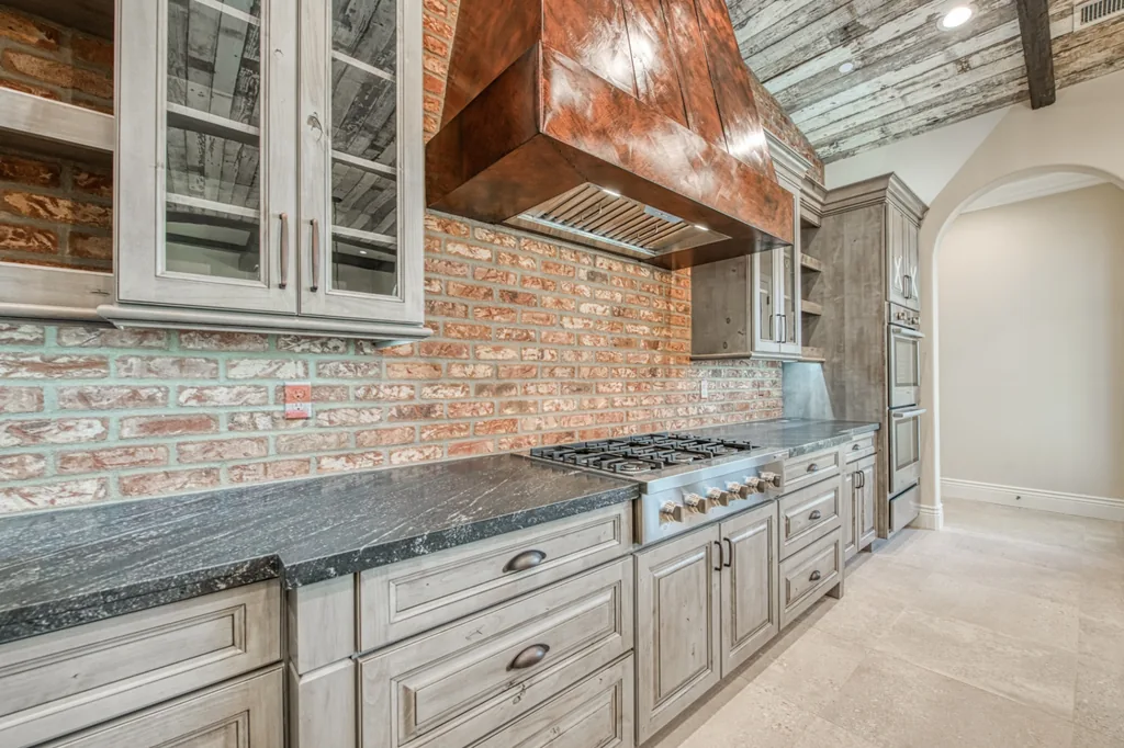 Professional range wall with copper hood and brick surround in the Devonshire Estate kitchen.