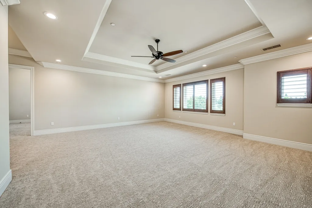 Primary bedroom at Devonshire Estate with a coffered tray ceiling and plantation shutters.