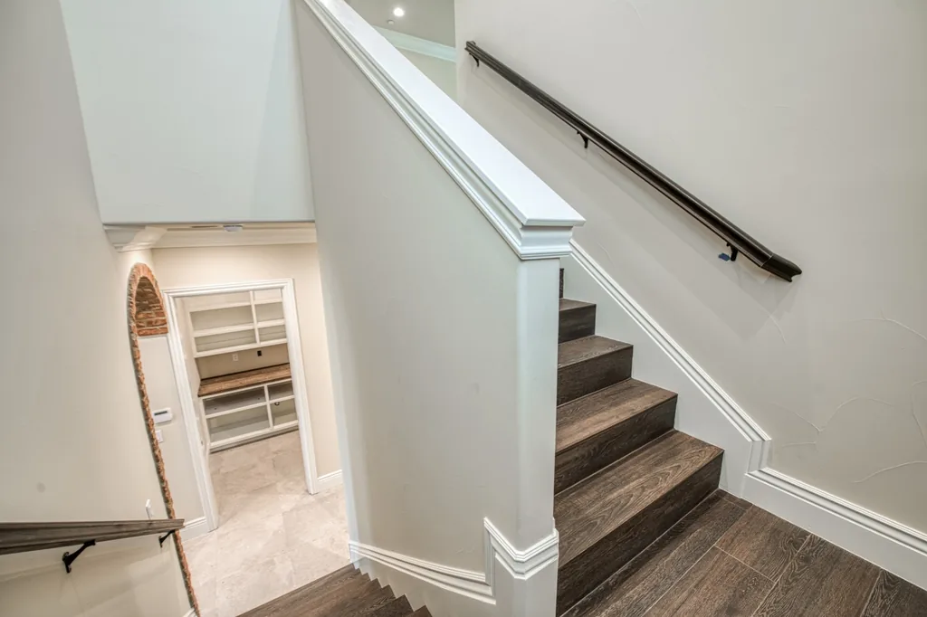 Staircase with wood treads and a bronze handrail at Devonshire Estate.