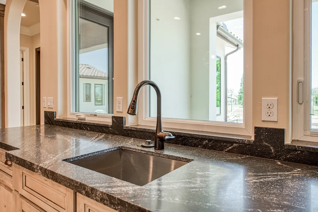 Wet bar with dark granite counters and bronze fixtures at Devonshire Estate in Fresno, California.
