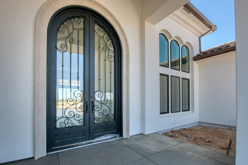 Arched wrought-iron and glass front entry door with cast stone surround at Kings Estate.