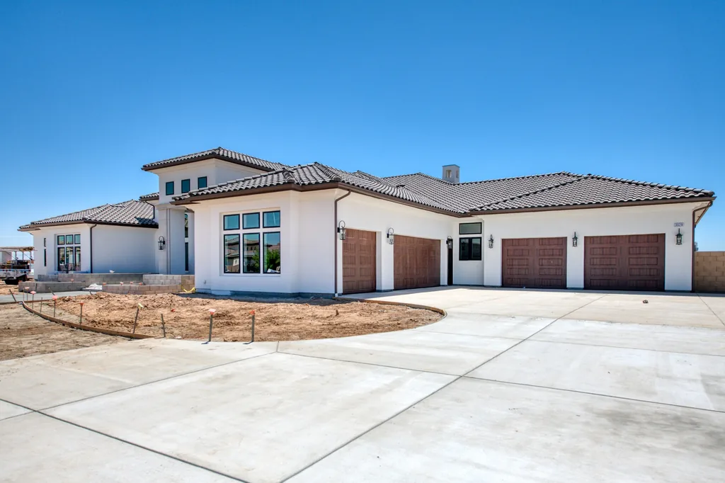 Front elevation of Kings Estate with tile hip roof, four-car garage, and circular concrete drive in Clovis, California.