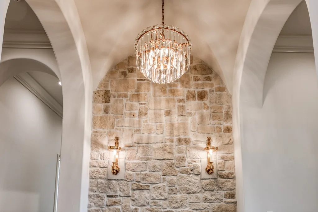 Plaster groin vault over a stone niche with crystal chandelier and brass sconces at Kings Estate.