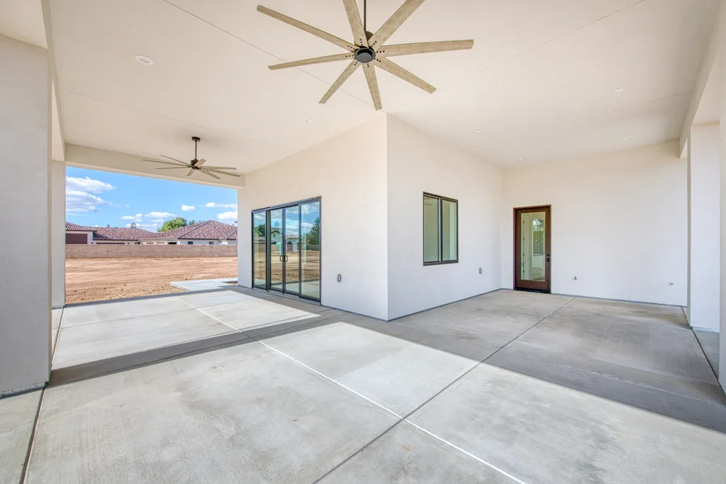 Covered outdoor living patio with beamed ceiling and fan at Queens Estate.