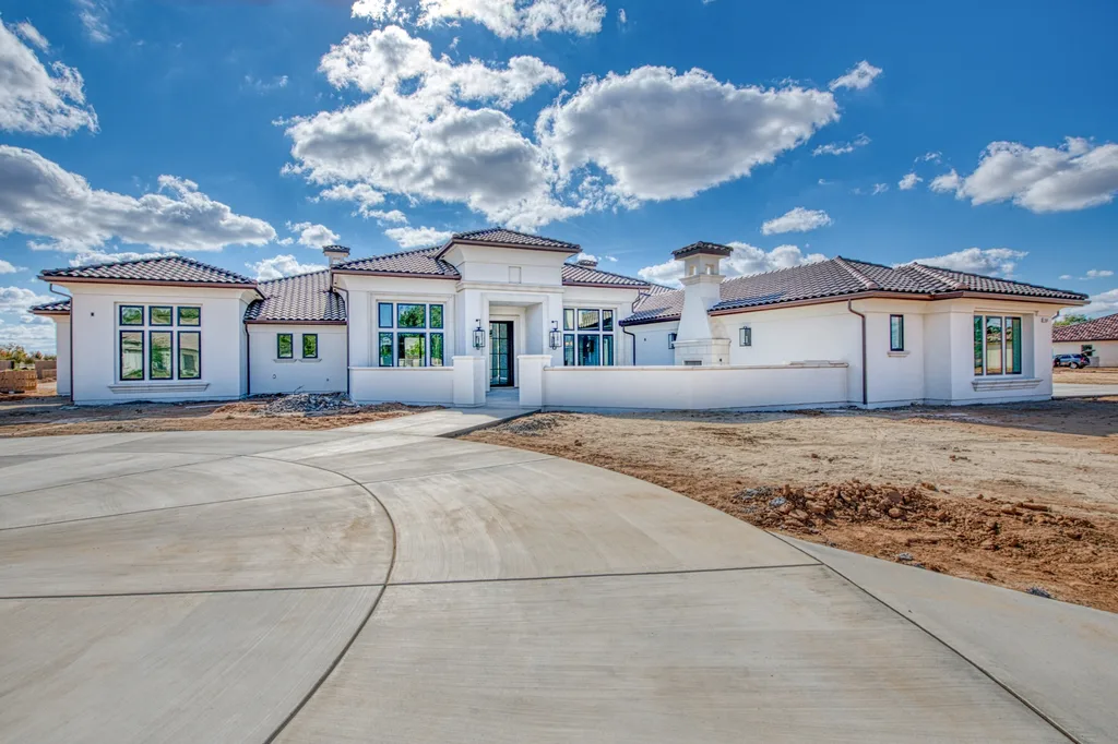 Front elevation of Queens Estate, a single-story custom home with a grey tile hip roof and stone entry portico in Clovis, California.