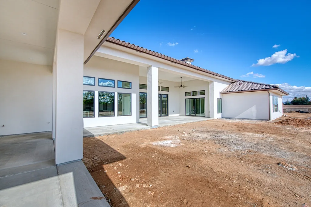 Rear covered loggia and patio overlooking the yard at Queens Estate.