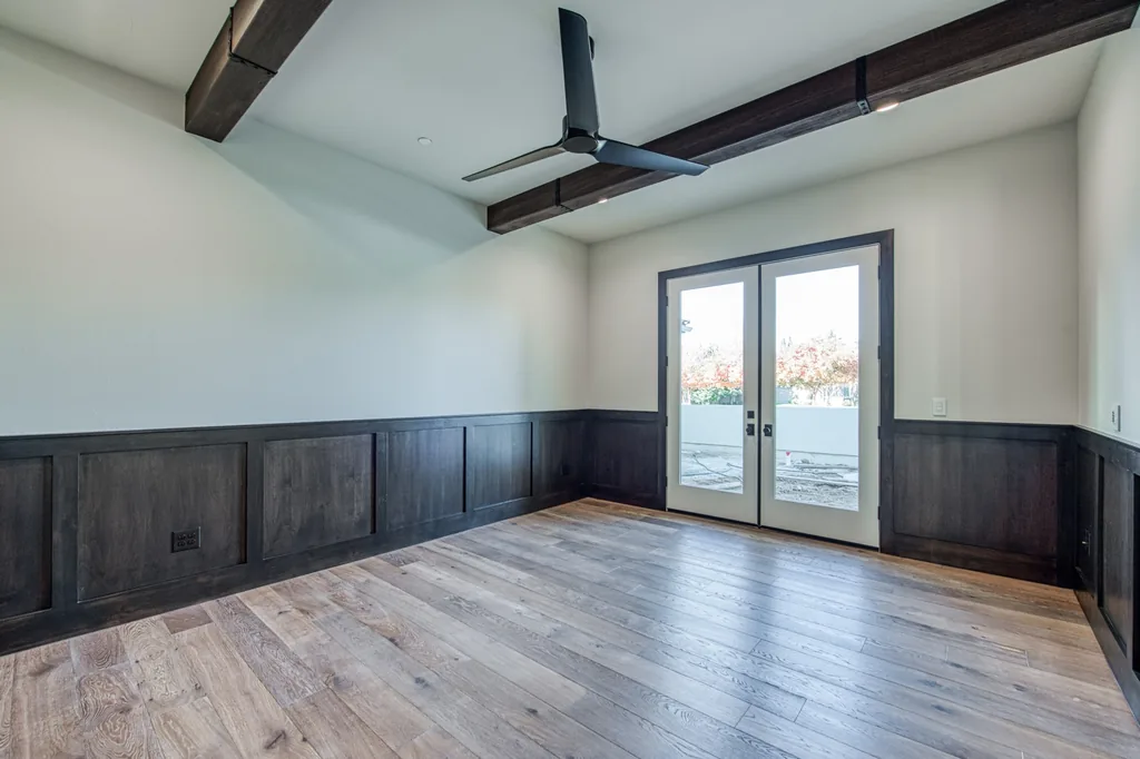 Formal dining room with stained wood wainscoting, beamed ceiling, and French doors.