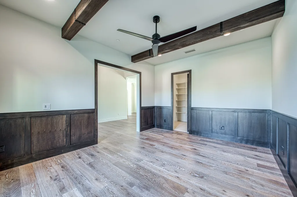 Formal room with full wood wainscoting, beamed ceiling, and built-in niche.