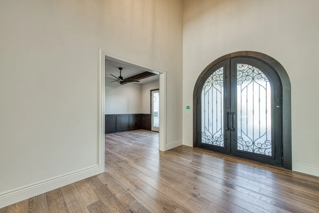 Foyer looking toward the arched iron entry doors and wide-plank oak flooring.