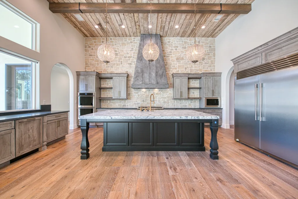 Kitchen with sculpted hood, crystal globe pendants, and marble-topped island.