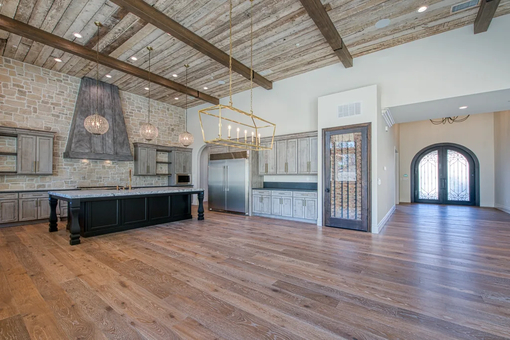 Kitchen with stone range hood and dark island open to the great room.