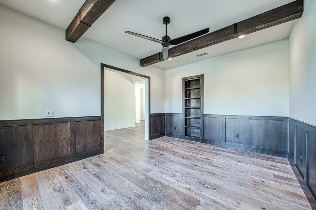Study with stained wood wainscoting and recessed built-in shelving.