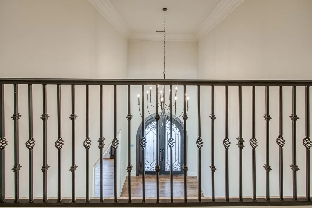 Upper landing with forged iron railing overlooking the entry foyer below.