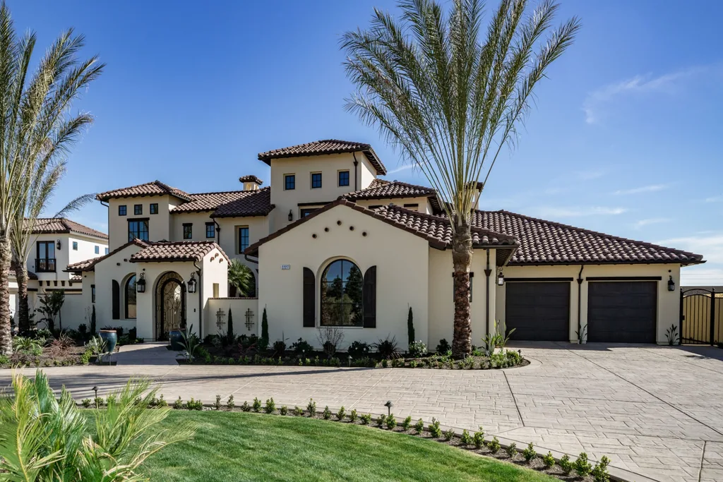 Front elevation of Spey Valley Estate I with tile roof, arched entry, and mature palms in Fresno, California.