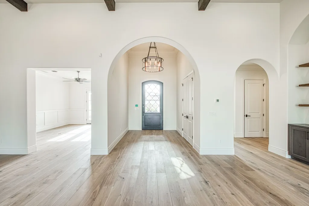 Entry foyer framed by a plaster arch with iron entry door and wide-plank oak floors.