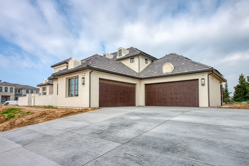 Front elevation of Spey Valley Estate II with stone accents and dark stained garage doors.