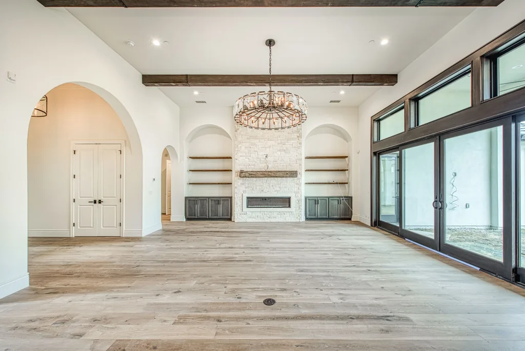 Great room with iron chandelier, arched alcoves, and stone fireplace.