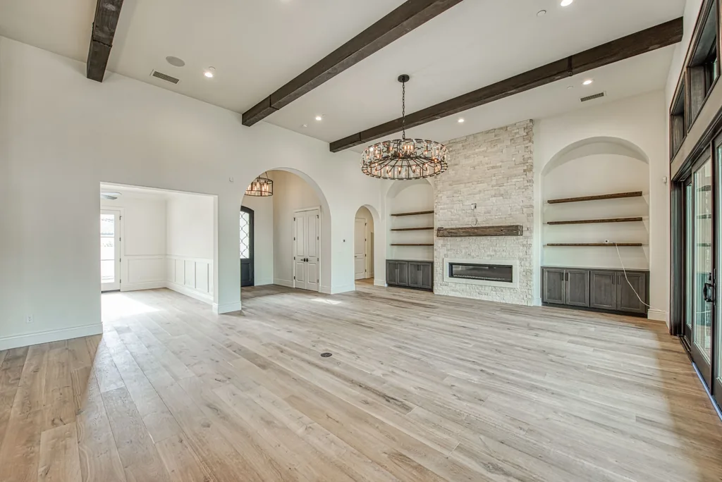 Great room with stacked stone fireplace flanked by arched built-in shelving.