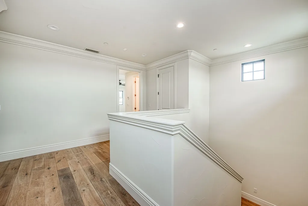 Stair landing with oak flooring and clean white walls.