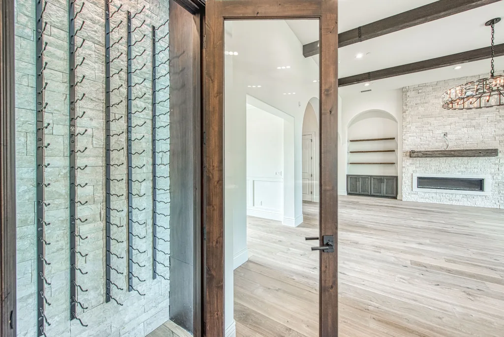 Wine room with stone walls, iron racking, and a stained glass door.