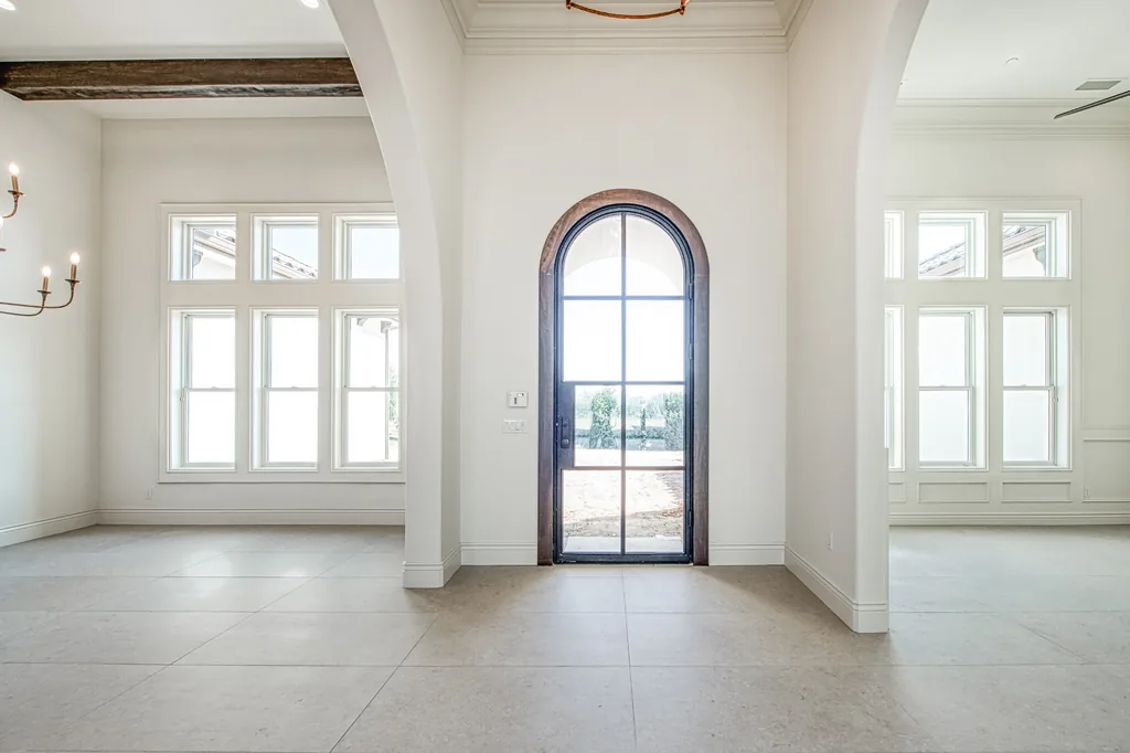 Entry foyer with a tall arched iron and glass front door flanked by windows at Willow Bluff Estate.