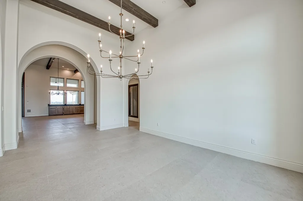 Formal dining room with wrought-iron chandelier and wood-beamed ceiling.