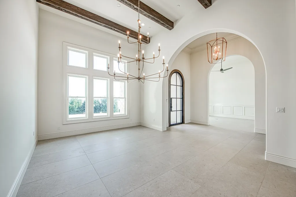 Formal room with tall arched windows, iron chandelier, and arched entry.