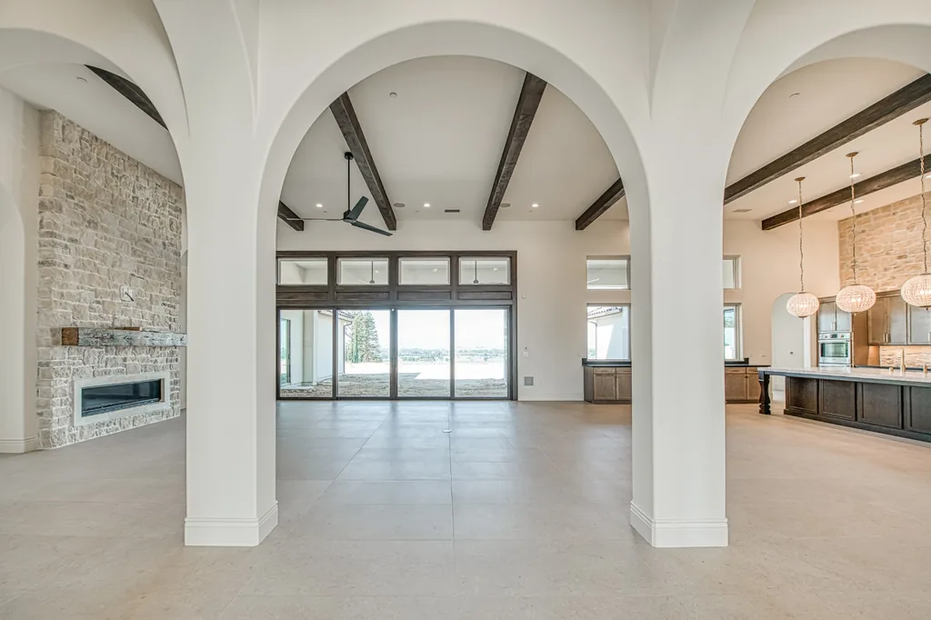Great room with stone fireplace, timber ceiling beams, and sliding glass doors.