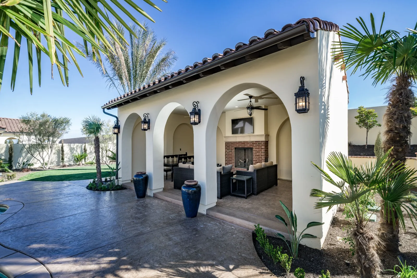 Detached accessory dwelling unit with arched loggia, tile roof, and outdoor fireplace designed to complement the primary residence.