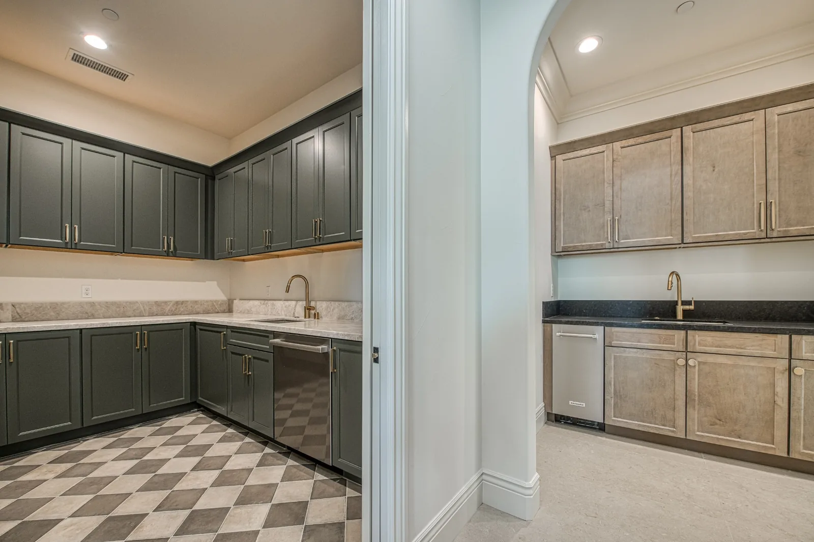 Renovated butler's pantry and prep kitchen with green and stained wood cabinetry, stone countertops, and updated brass fixtures.